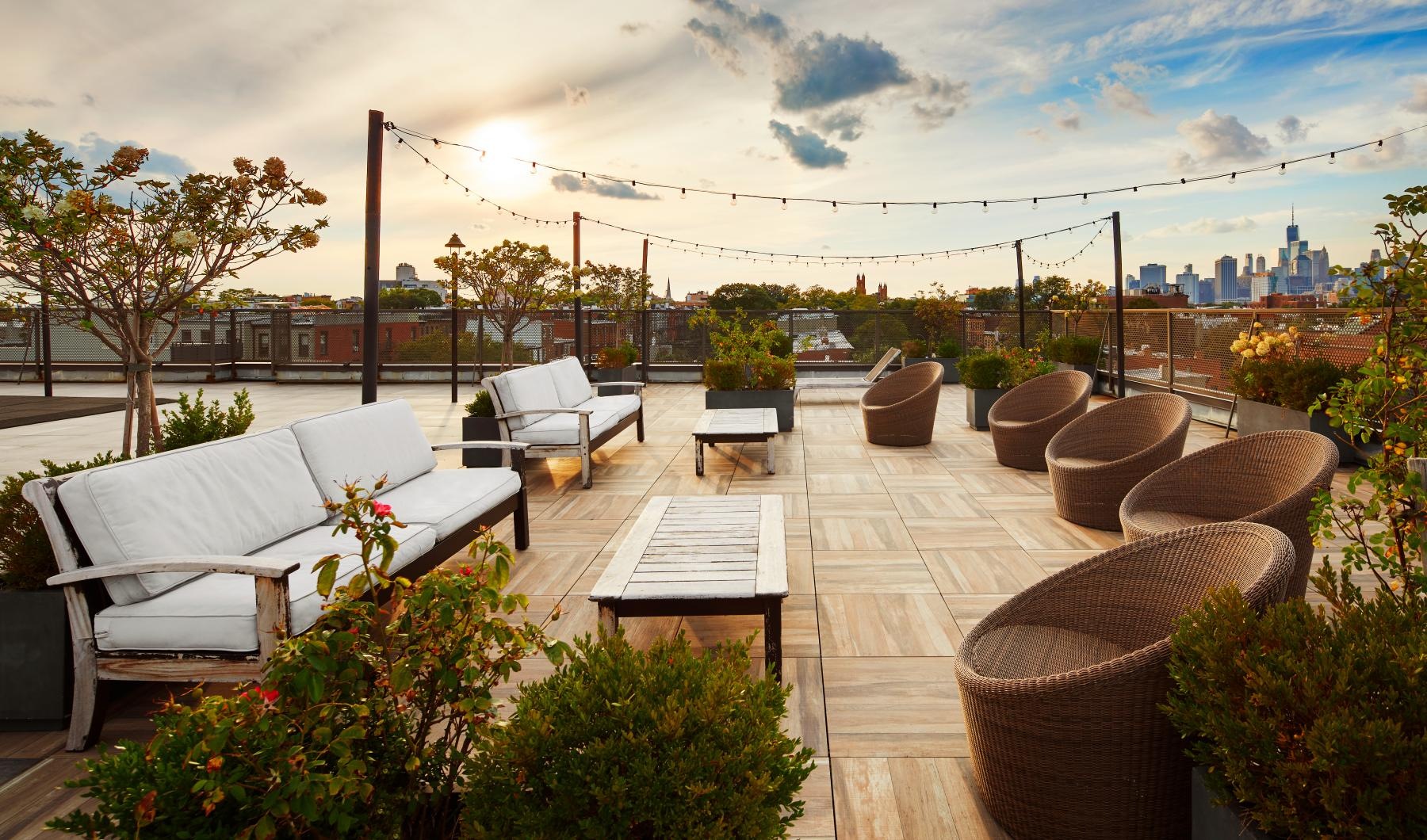 a patio with chairs and tables and plants with a city in the background